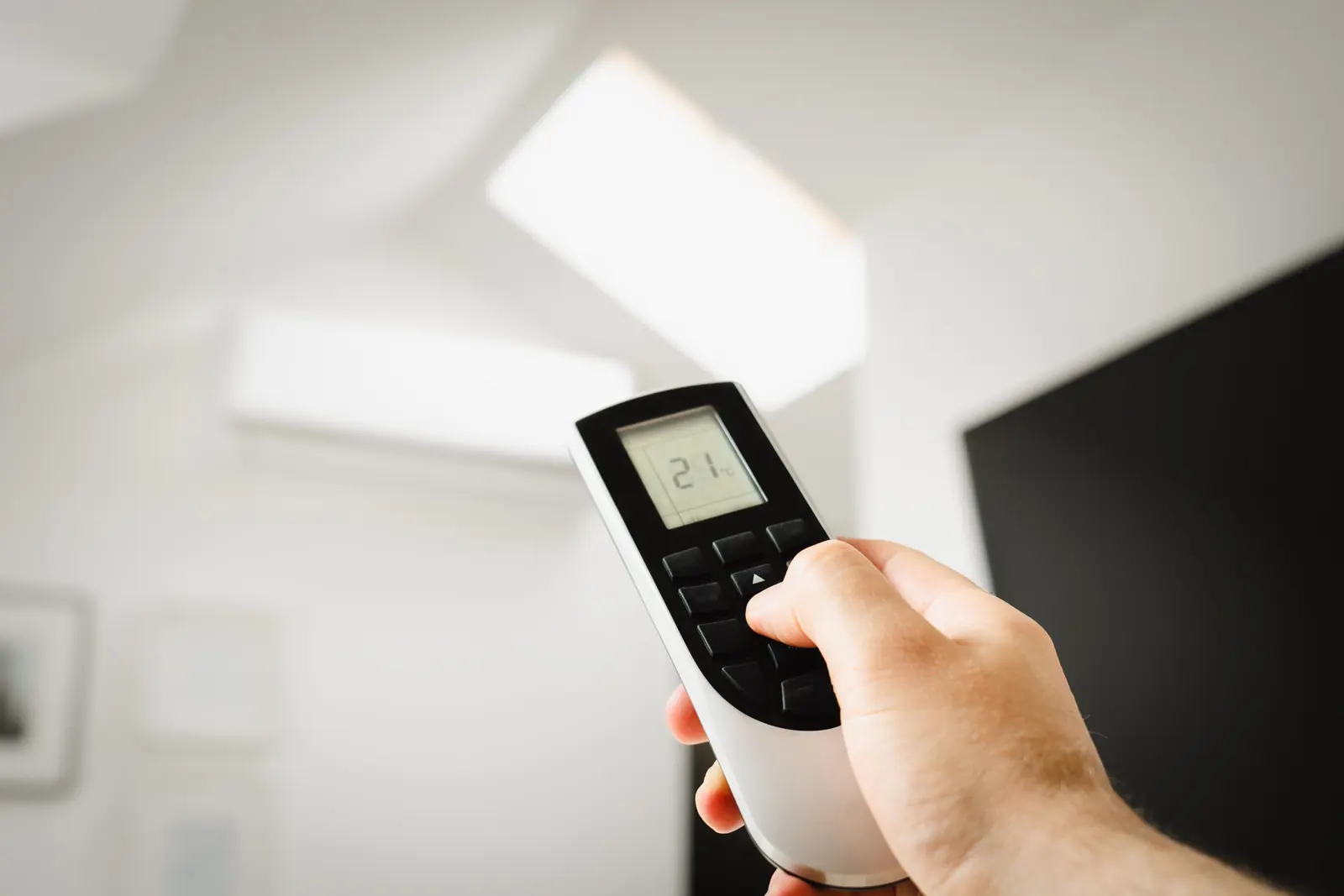 Main réglant un climatiseur avec une télécommande