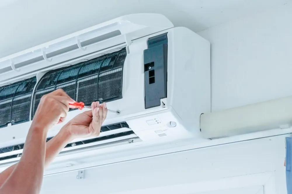 Hands servicing an indoor air conditioning unit